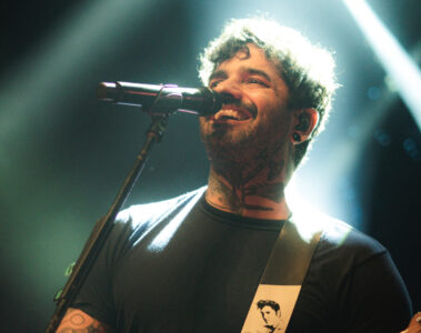 Lucas Silveira, vocalista da Fresno, em apresentação ao vivo com guitarra e iluminação dramática no palco