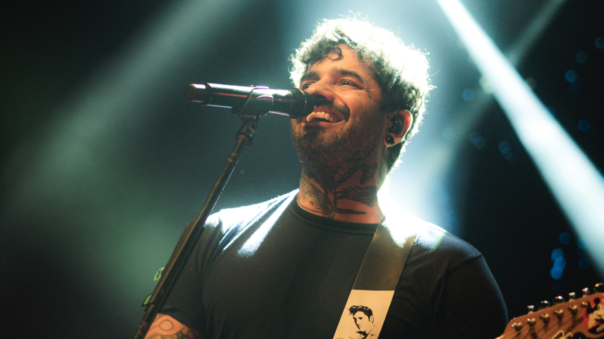 Lucas Silveira, vocalista da Fresno, em apresentação ao vivo com guitarra e iluminação dramática no palco