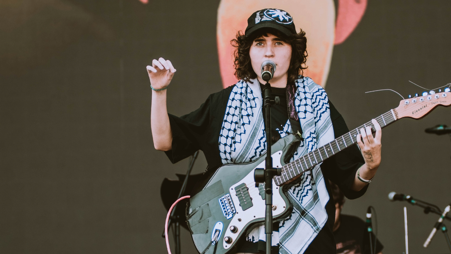 Sophia Chablau no Lollapalooza 2025 com keffiyeh palestino e guitarra, durante performance com protesto político.