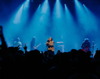 Banda Adorável Clichê se apresenta com luzes azuis intensas para um público atento na Casa Natura Musical em São Paulo, em show marcante de shoegaze.