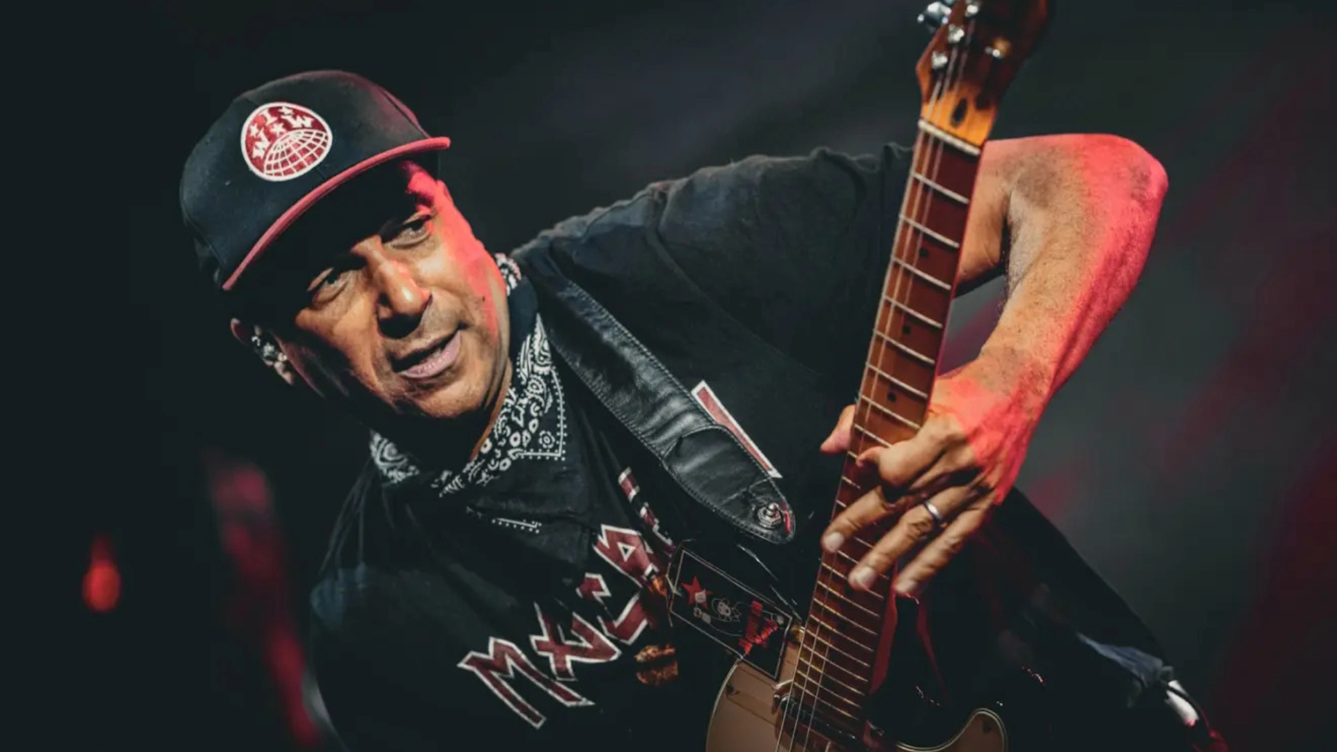 Tom Morello tocando guitarra ao vivo com expressão intensa durante show.