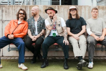 Banda IDLES posa sentada lado a lado antes do lançamento da música “Rabbit Run”, parte da trilha do filme Caught Stealing de Darren Aronofsky.