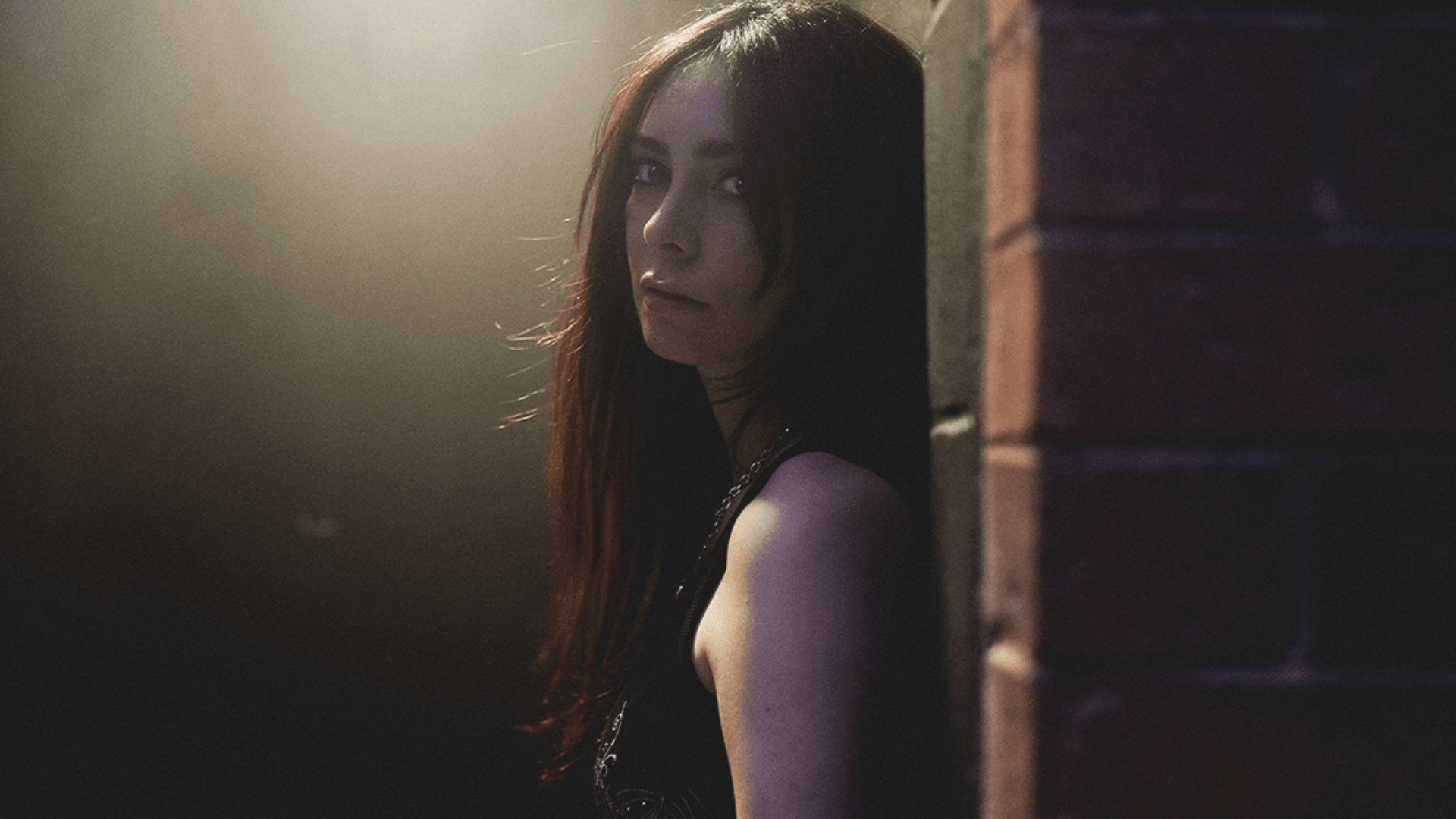 LØLØ posa em ambiente sombrio com iluminação suave, promovendo o single the devil wears converse