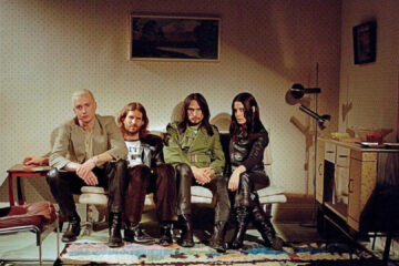 Banda Wolf Alice sentada em um sofá em uma sala retrô, foto promocional de The Sofa tirada por Rachel Fleminger Hudson