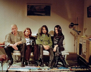 Banda Wolf Alice sentada em um sofá em uma sala retrô, foto promocional de The Sofa tirada por Rachel Fleminger Hudson