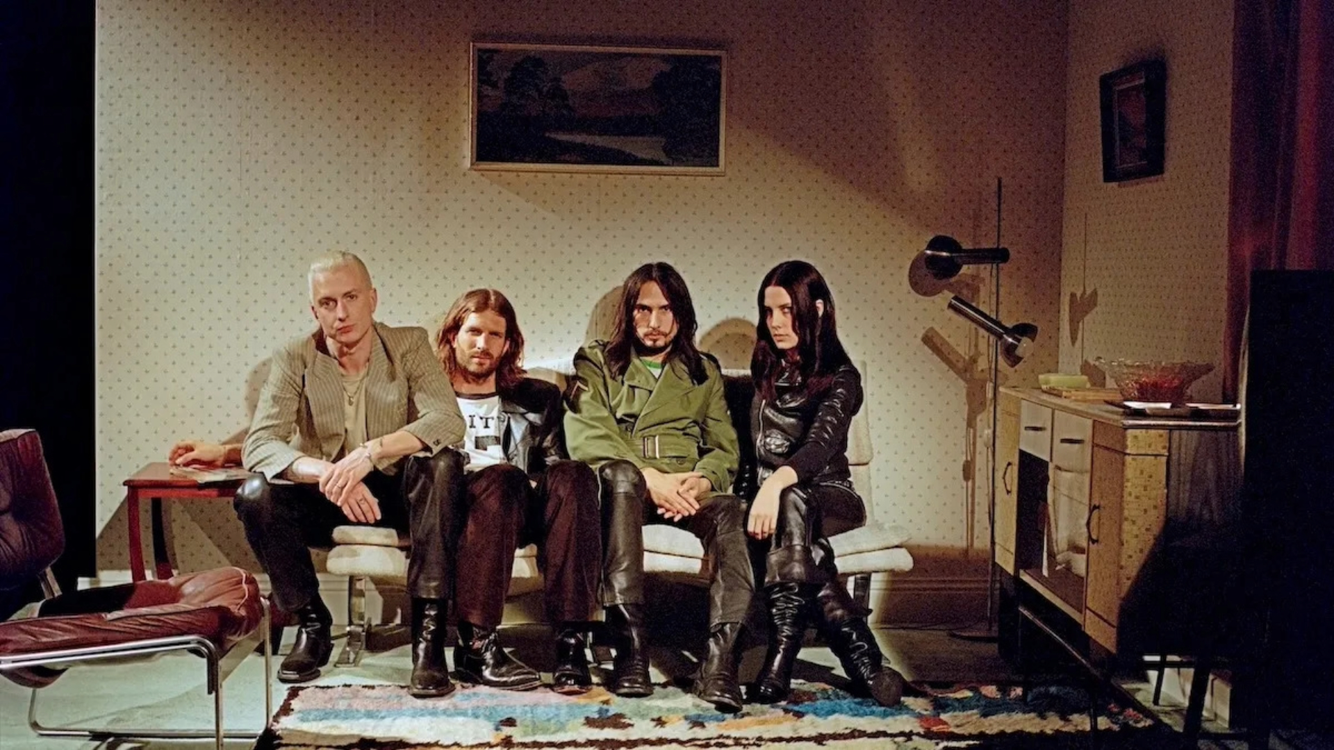 Banda Wolf Alice sentada em um sofá em uma sala retrô, foto promocional de The Sofa tirada por Rachel Fleminger Hudson