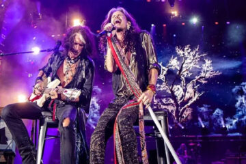 Joe Perry e Steven Tyler do Aerosmith se apresentam ao vivo em show com iluminação roxa, em possível turnê de despedida