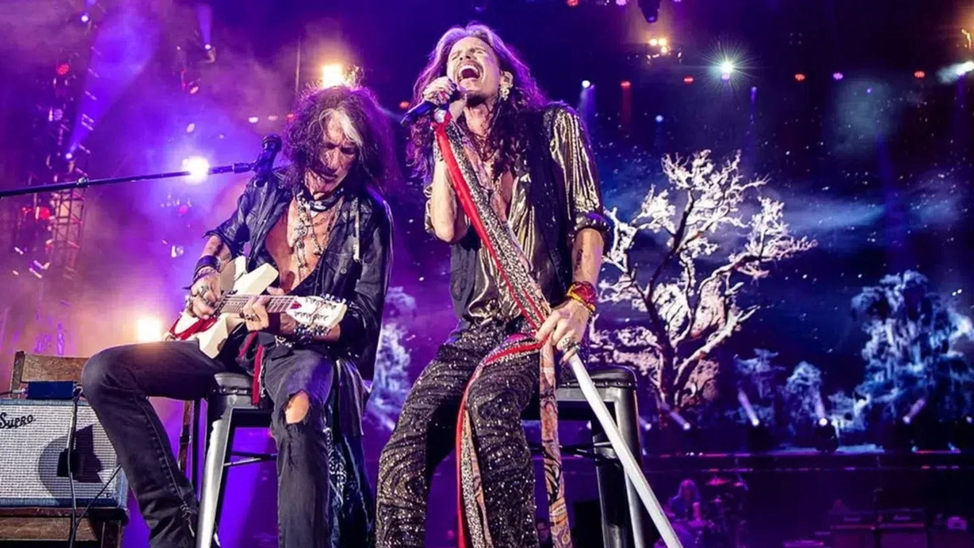 Joe Perry e Steven Tyler do Aerosmith se apresentam ao vivo em show com iluminação roxa, em possível turnê de despedida