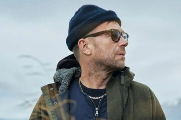 Damon Albarn usando gorro e óculos escuros em ambiente externo