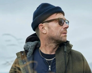 Damon Albarn usando gorro e óculos escuros em ambiente externo
