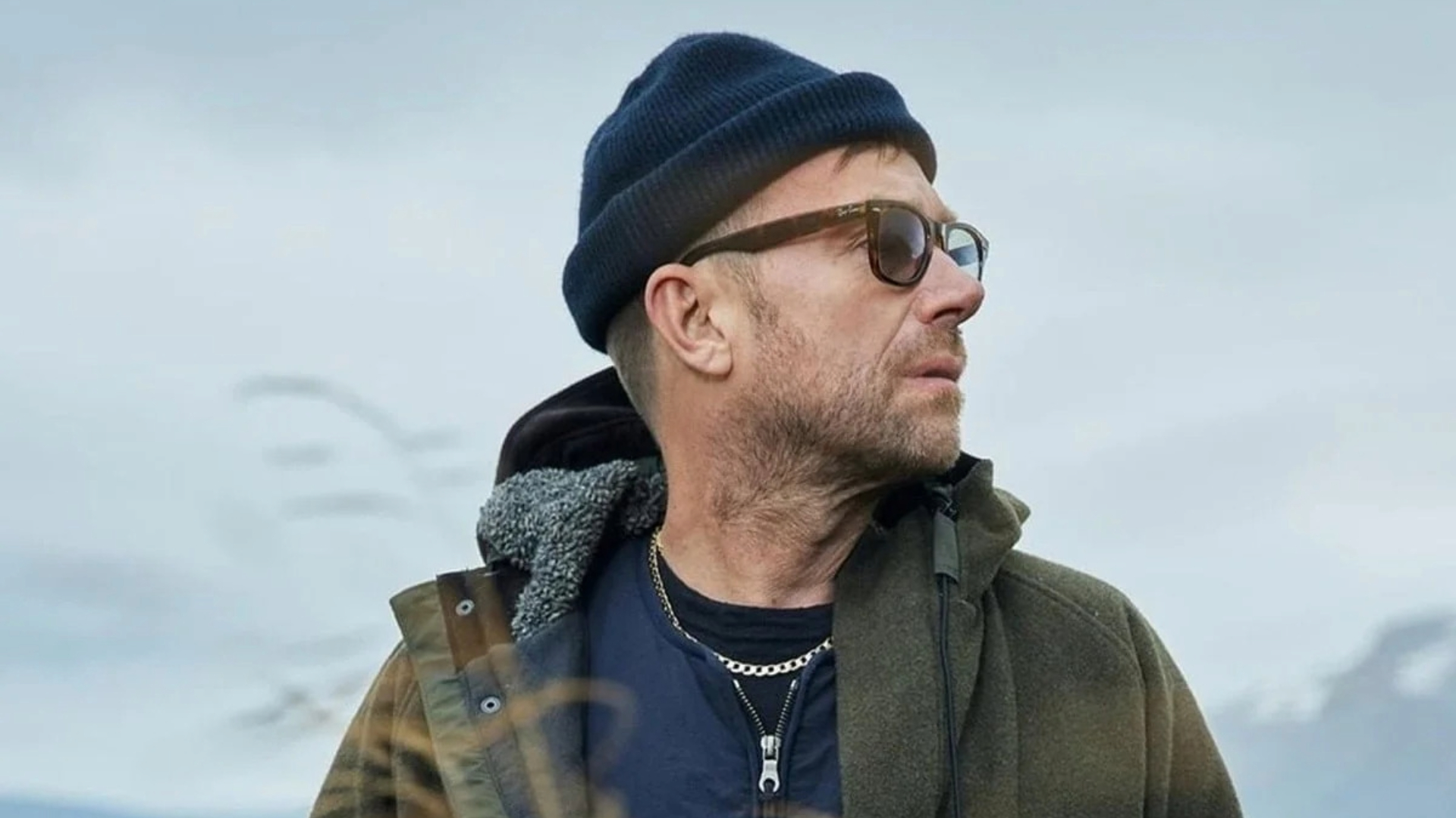 Damon Albarn usando gorro e óculos escuros em ambiente externo