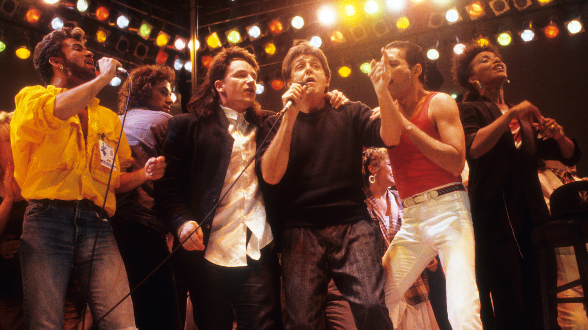 Freddie Mercury, Paul McCartney, Bono e George Michael cantando juntos no palco do Live Aid, em 1985