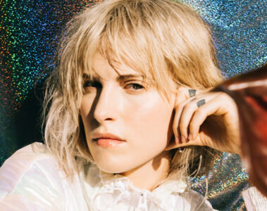 Hayley Williams em foto promocional com fundo brilhante, usando jaqueta branca e olhar intenso — crédito: Lindsey Byrnes