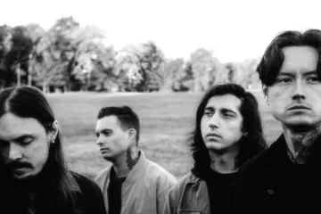 Os integrantes do Bad Omens posam em um campo, em foto promocional em preto e branco do single “Impose”.