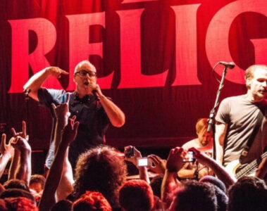 Bad Religion se apresenta ao vivo em show de punk rock, com vocalista e baixista à frente do palco diante do público.