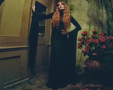 Florence Welch posa em um cenário sombrio ao lado de um vaso de rosas vermelhas para divulgar o novo single One of the Greats e o álbum Everybody Scream.