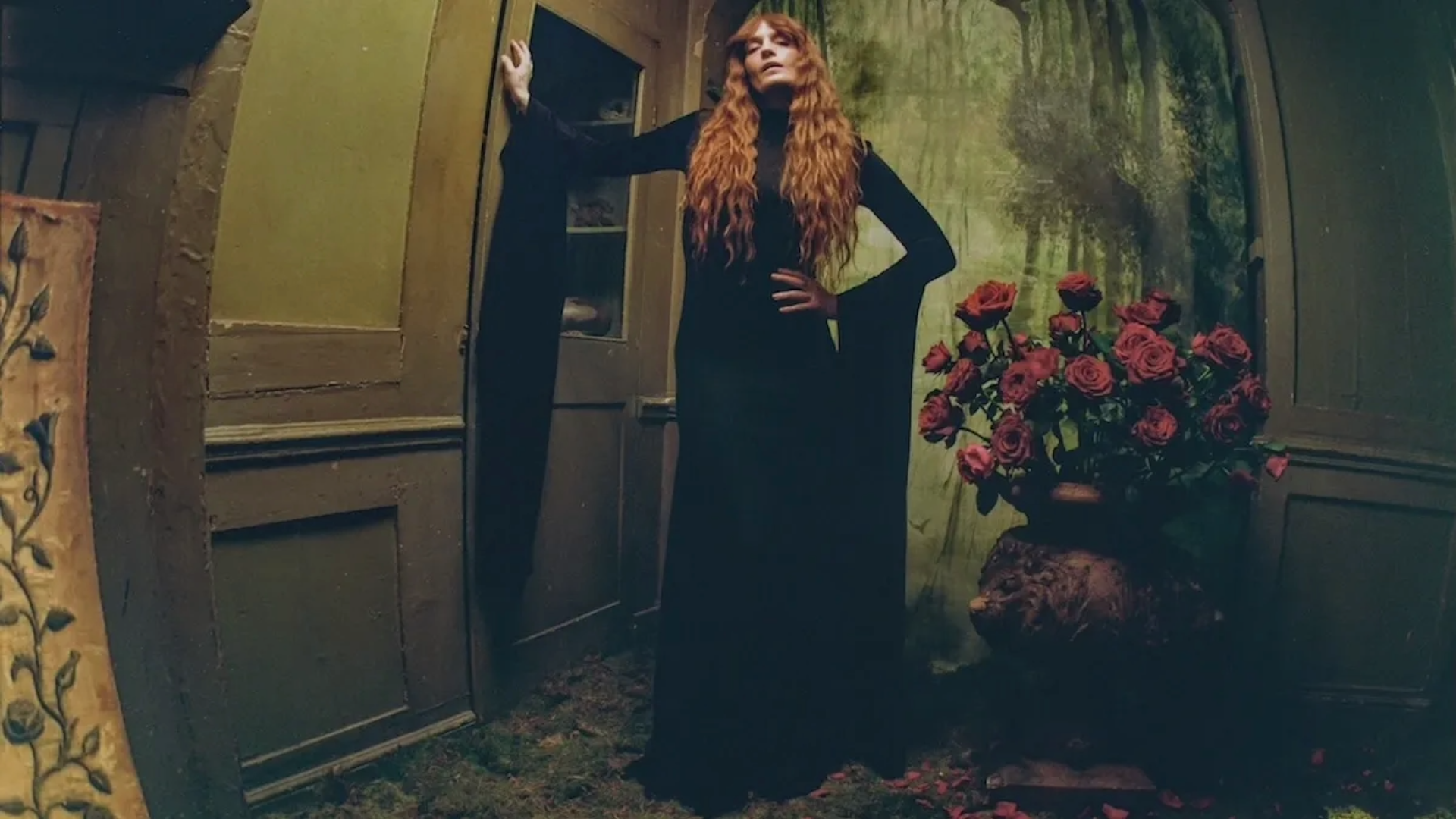 Florence Welch posa em um cenário sombrio ao lado de um vaso de rosas vermelhas para divulgar o novo single One of the Greats e o álbum Everybody Scream.