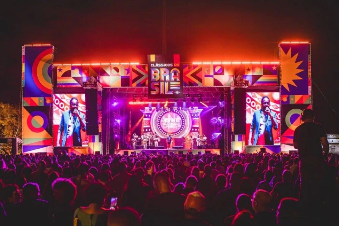 Palco do Festival Clássicos do Brasil 2024 na Marina da Glória, iluminado à noite com público vibrante assistindo aos shows.