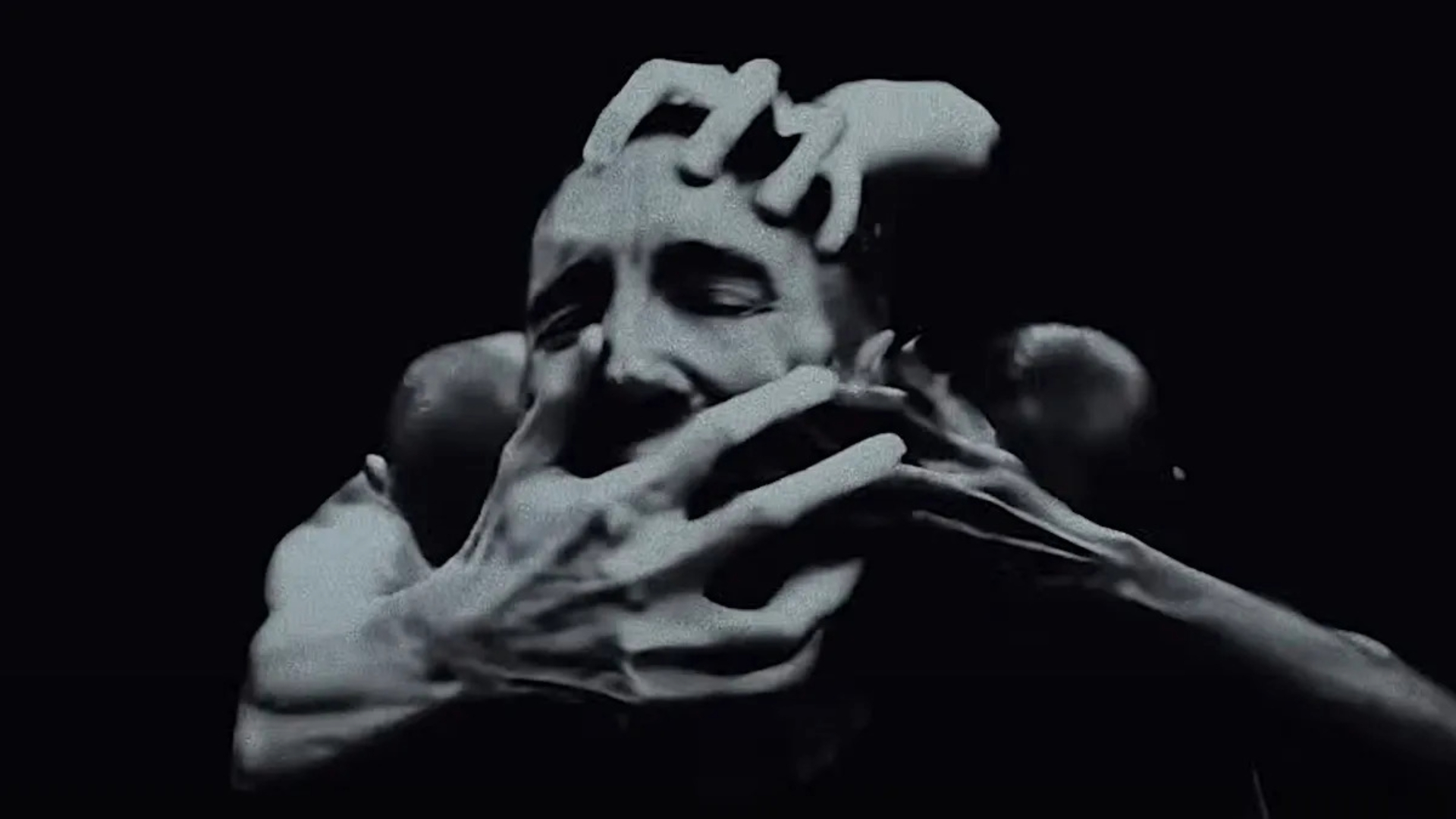 Cena do videoclipe de “As Alive As You Need Me To Be”, do Nine Inch Nails, com Trent Reznor cercado por várias mãos.