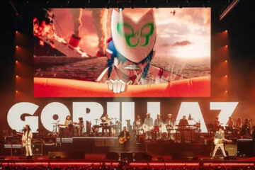 Show do Gorillaz em Londres com telão exibindo animações e a banda se apresentando ao vivo no palco.