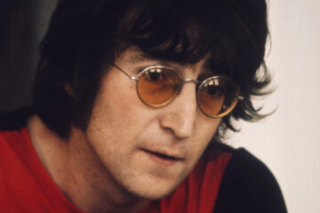 John Lennon usando óculos de lentes laranja durante entrevista nos anos 1970.