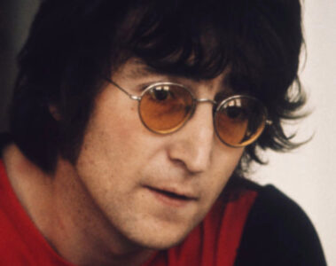 John Lennon usando óculos de lentes laranja durante entrevista nos anos 1970.