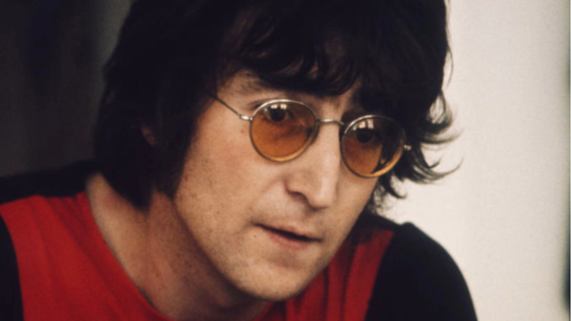 John Lennon usando óculos de lentes laranja durante entrevista nos anos 1970.