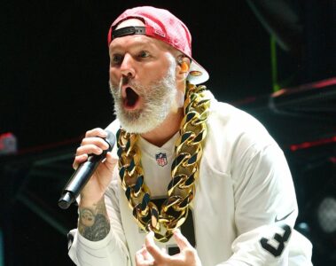 Fred Durst, vocalista do Limp Bizkit, se apresenta ao vivo usando boné vermelho para trás, corrente dourada e camiseta branca.