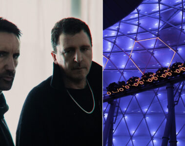 Trent Reznor e Atticus Ross, do Nine Inch Nails, ao lado da montanha-russa Tron na Disney iluminada em azul.