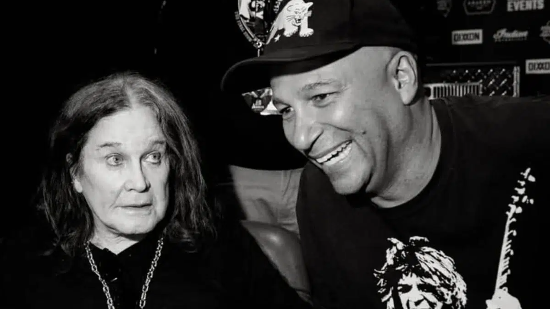 Ozzy Osbourne e Tom Morello sorrindo juntos nos bastidores após show do Black Sabbath.