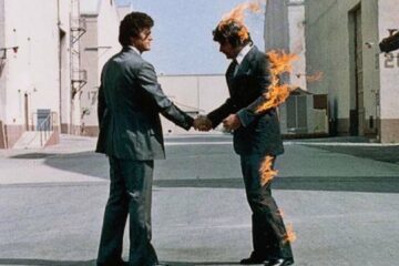 Capa do álbum Wish You Were Here, do Pink Floyd, mostrando dois homens de terno apertando as mãos enquanto um deles está em chamas.