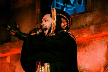 The Weeknd durante apresentação ao vivo, vestindo manto preto bordado, parte da turnê After Hours Til Dawn.