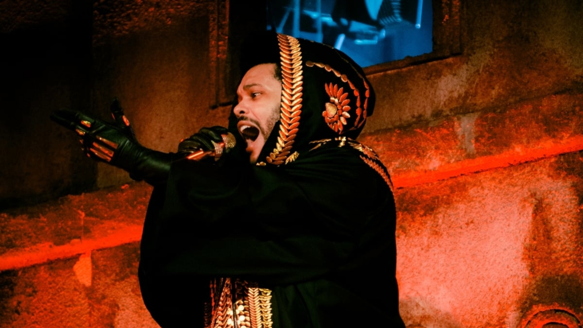 The Weeknd durante apresentação ao vivo, vestindo manto preto bordado, parte da turnê After Hours Til Dawn.