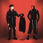 Capa promocional de Breach (2025), álbum do Twenty One Pilots, com Tyler Joseph e Josh Dun em cenário vermelho, explorando a saga de Clancy.