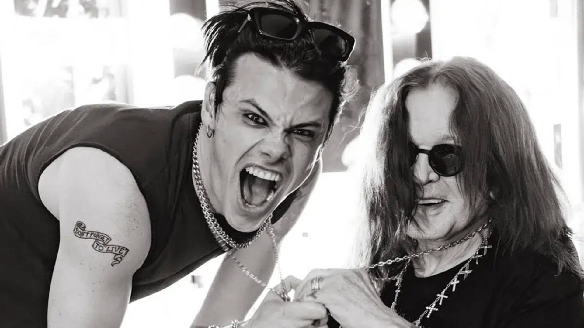 Yungblud e Ozzy Osbourne juntos em foto preto e branco, sorrindo e segurando correntes, mostrando amizade e conexão.