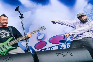 Fred Durst e Sam Rivers durante show do Limp Bizkit, em performance vibrante com luzes e fumaça no palco.