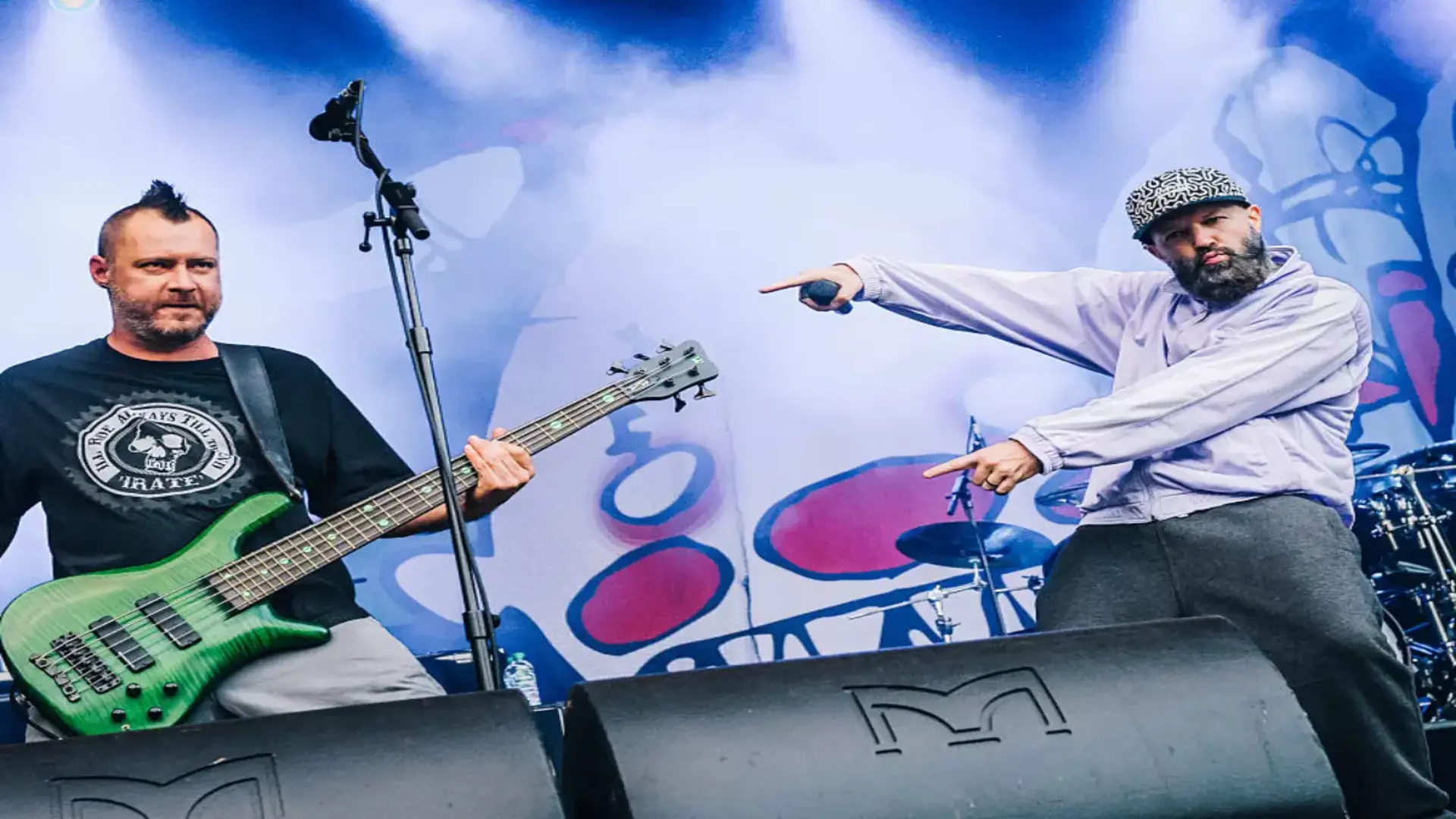 Fred Durst e Sam Rivers durante show do Limp Bizkit, em performance vibrante com luzes e fumaça no palco.
