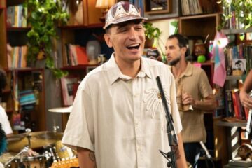João Gomes sorri durante sua apresentação de estreia no Tiny Desk Brasil, acompanhado por banda em ambiente intimista no escritório do Google.