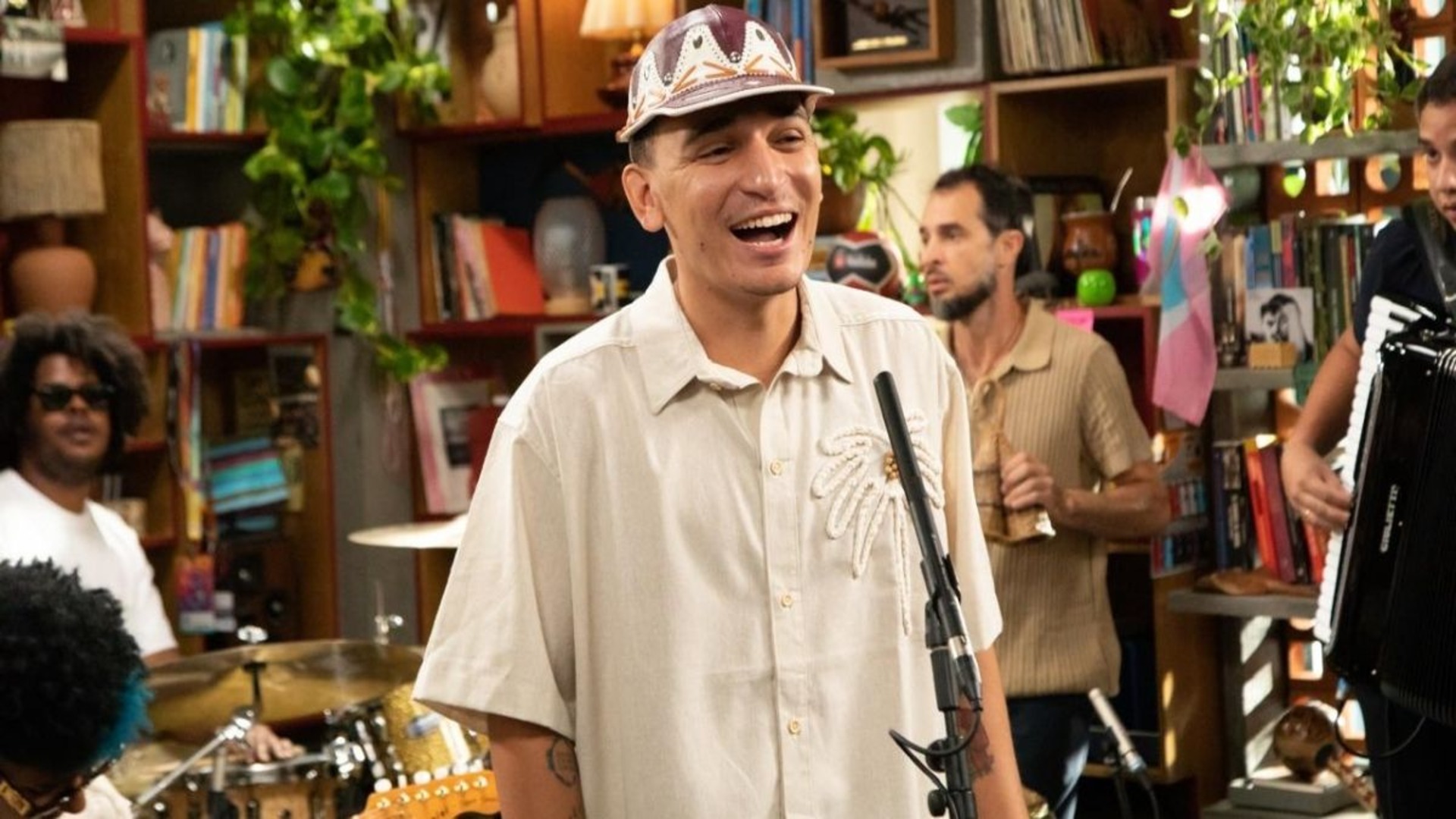 João Gomes sorri durante sua apresentação de estreia no Tiny Desk Brasil, acompanhado por banda em ambiente intimista no escritório do Google.