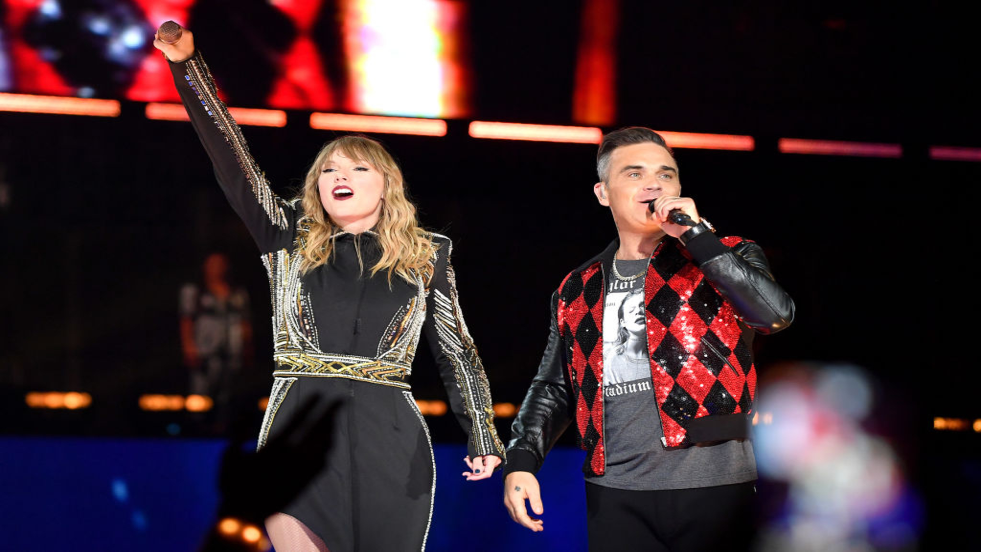 Taylor Swift e Robbie Williams se apresentam juntos no palco durante show em Londres.