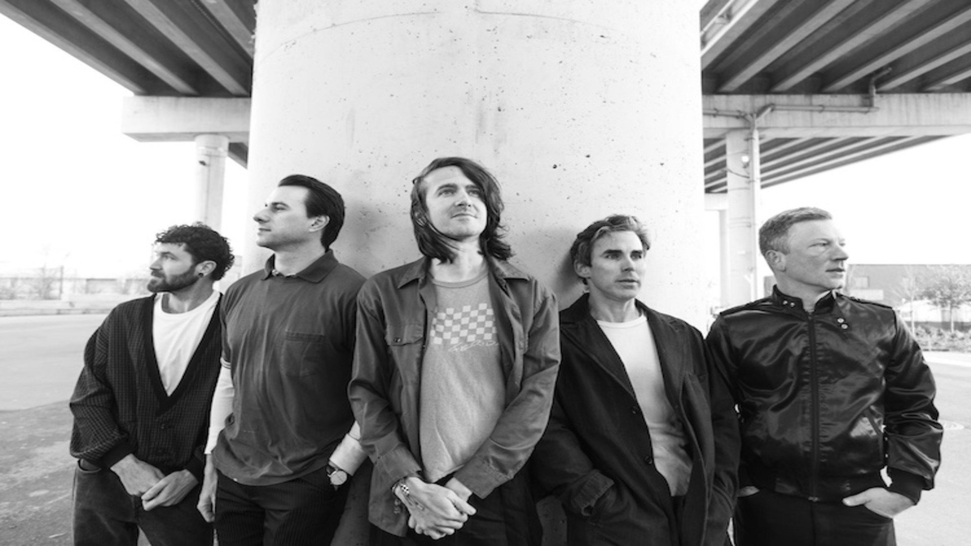 Foto em preto e branco da banda Mayday Parade posando sob um viaduto, divulgando o single “Promises” do álbum Sad (Crédito: Eli Ritter).