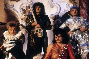 Queen em registro promocional nos anos 80, com Freddie Mercury, Brian May, Roger Taylor e John Deacon usando figurinos teatrais e posando em cenário barroco. Foto: Queen Productions Ltd.