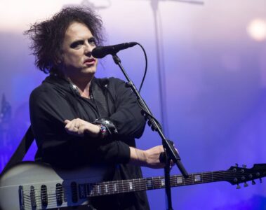 Robert Smith, vocalista e guitarrista do The Cure, se apresenta ao vivo em show com guitarra em mãos.
