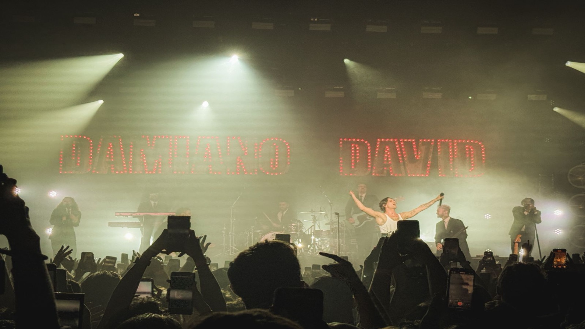 Damiano David se apresenta no palco do Tokyo Marine Hall em São Paulo durante sua turnê solo FUNNY Little FEARS, com luzes douradas e o público vibrando.