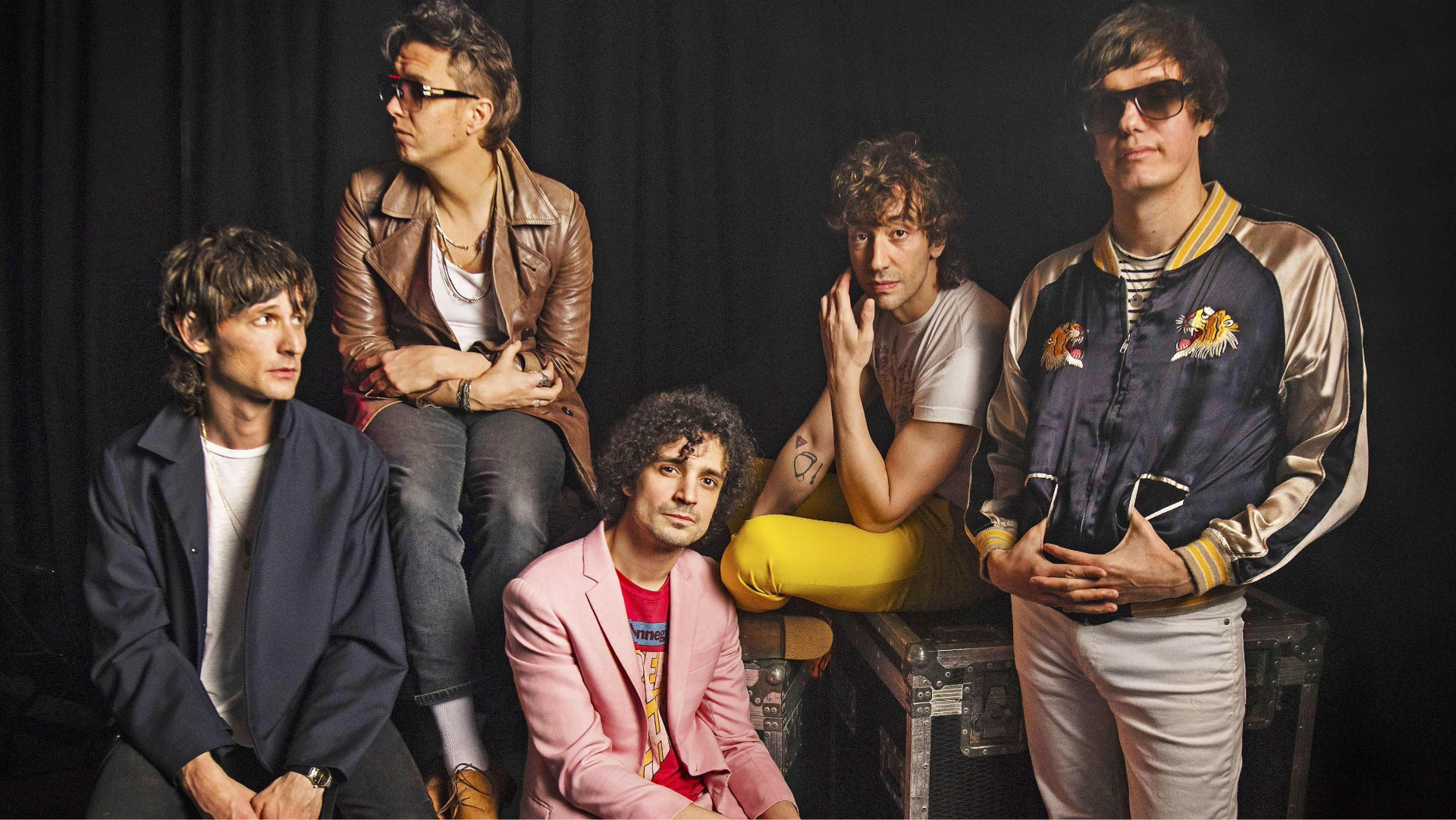 Foto do The Strokes posando juntos; Julian Casablancas e o guitarrista Nick Valensi aparecem com os outros integrantes em um estúdio.