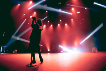 Show do Molchat Doma em São Paulo com vocalista Egor Shkutko em silhueta sob luzes vermelhas e feixes estroboscópicos no palco.