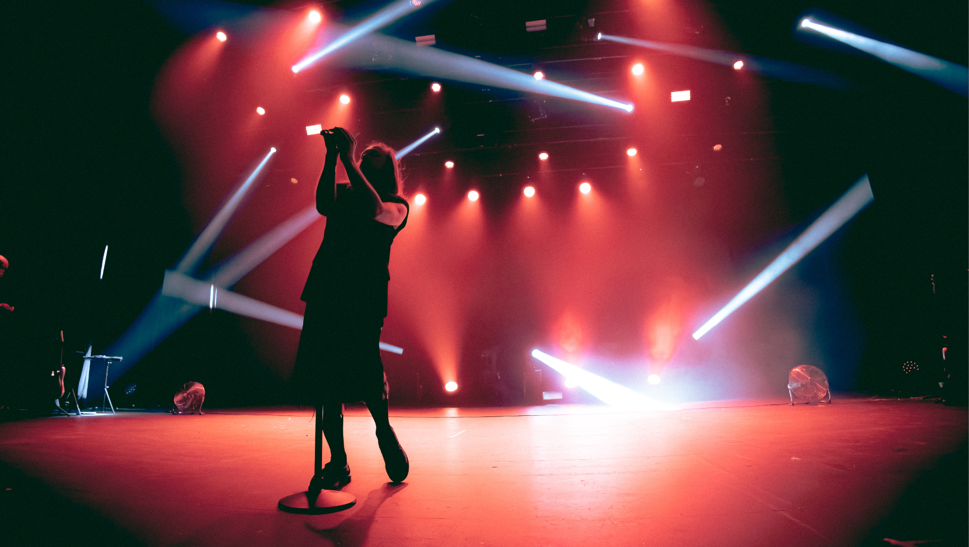 Show do Molchat Doma em São Paulo com vocalista Egor Shkutko em silhueta sob luzes vermelhas e feixes estroboscópicos no palco.