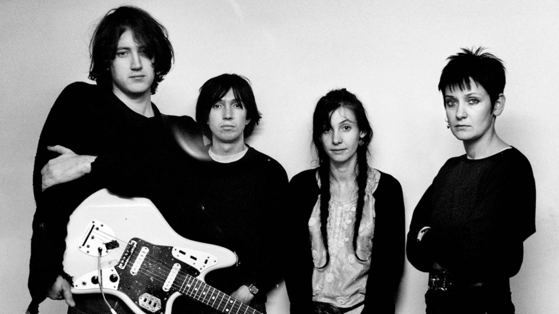 Foto em preto e branco do My Bloody Valentine em 1990, com Kevin Shields segurando uma guitarra ao lado dos outros integrantes. Crédito: Steve Gullick.