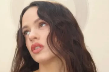 Rosalía em close-up com expressão contemplativa e efeito visual que remete a um halo, representando o conceito espiritual do álbum “Lux”.