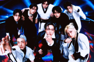 Grupo Stray Kids posando em estúdio com iluminação futurista, vestindo roupas em preto e branco, em foto promocional de 2024.